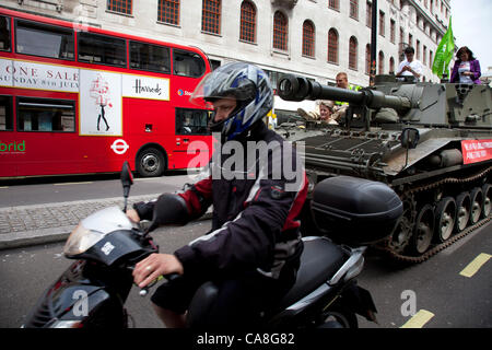 London, UK. Mittwoch, 27. Juni 2012. Moped geht den Tank während entlang The Strand. Aktivisten und Unterstützer von Oxfam und Amnesty International, als Teil der Koalition Querlenker fahren einen Abt Pistole Tank um zentrale London die Notwendigkeit für eine globale Waffen Handel Vertrag (AT Stockfoto