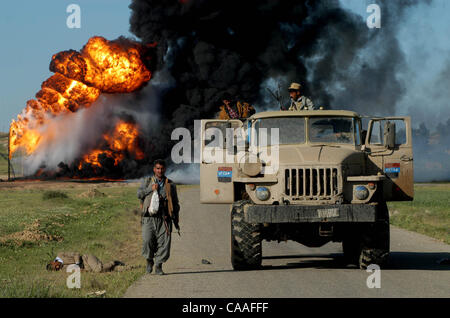 10. April 2003; Kirkuk, Irak; Feiern in den Straßen von Kirkuk im Nordirak als kurdische Kräfte Sweep in der Öl-Stadt mit wenig Widerstand. Saddam Fedajin Kämpfer (auf Links Fedayeen LKW liegen) wurde erschossen und von lokalen Milizen in Kirkuk Tod überlassen. Feuer im Hintergrund ist ein Öl-Feuer. Othe Stockfoto