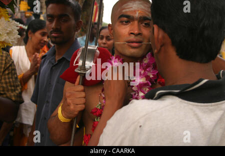 KUALA LUMPUR, MALAYSIA 5. Februar 2004 seine Zunge montiert mit schweren Cavadi auf seinen Schultern, 25 Jahr alt Gunasegran erhält Unterstützung von Freunden, wie er zum ersten Mal in das Thaipusam Festival, Februar 5 beteiligt sich. 2004. 30 oder mehr Tage des Fastens und Stunden nach Durchführung der Cavadis erfordern Stockfoto