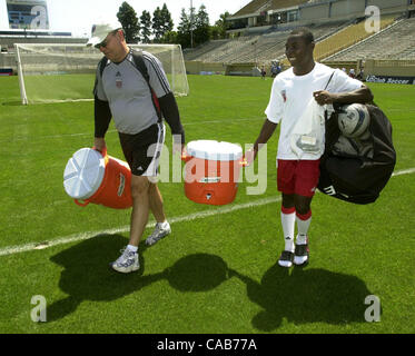 DC United Teamadministrator Ray Trifari (links) hilft 14-jährige Fußballspieler Freddy Adu (rechts) ein Wasserbehälter aus dem Feld nach dem Training im Spartan Stadium in San Jose, Kalifornien, auf Freitag, 30. April 2004 zu tragen. Tragen der Ausrüstung auf und abseits des Feldes gehört zu den Aufgaben des Seins ein ro Stockfoto