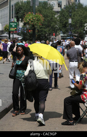 Gelben Regenschirm von einer Frau benutzt, um sich von der Sonne heute entlang der Sixth Avenue in Manhattan zu decken. Stockfoto