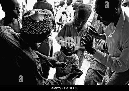 18. September 2010 - Kano, KANO, NIGERIA - Impfärzte BILYAMINU YAKUBA und SANI MOHAMMED, plädieren mit einem Kind unter fünf Jahren, sie zwei Tropfen des Polio-Impfstoffes auf seiner Zunge an einem stationären Impfstoff Standort verwalten zu lassen. Über die Fagge Verwaltungsgebiet, Ward Kwciri, Suche nach Chi auffächern Polio Impfärzte Stockfoto