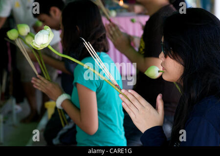 Thailändische Frauen beten mit gefalteten Händen, während sie Räucherstäbchen und Lotusblumen halten, um am Freitag, den 13.. April 2012, das thailändische Neujahr in einem buddhistischen Tempel in der Sukhumvit Road, Bangkok, Thailand, einzubringen. Bangkok feiert das thailändische Neujahr mit dem traditionellen Songkran Wasserfestival. Quelle: Kraig lieb Stockfoto