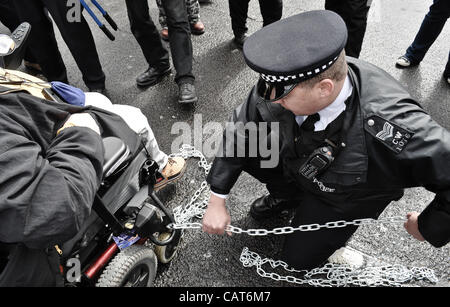 18.04.12, London, UK: ein Polizist entfernt Ketten aus einem Rollstuhl, da Behinderte Demonstranten Straßen am Trafalgar Square auf Fragen eingehen, sie konfrontiert sind, Inclluding Änderungen der Leistungen bei Erwerbsunfähigkeit blockieren. Stockfoto