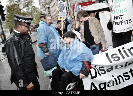 18.04.12, London, UK: ein Polizist im Gespräch mit einem Rollstuhlfahrer, der Teil einer kleinen Gruppe blockieren Straßen am Trafalgar Square aus Protest gegen Änderungen der Leistungen bei Invalidität. Stockfoto