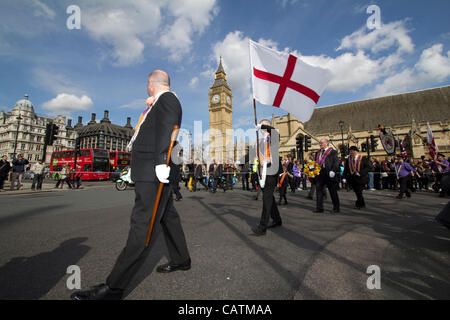 21.04.2012 London UK Protestanten in der Oranier-Orden marschieren durch die Londoner heute Orange Lodge, oder der Oranier loyal orange Reihenfolge marschieren durch London paradieren Vergangenheit Westminster Houses of Parliament und big Ben mit Flagge von England St. Georg Kreuz, Str. Georges Kreuz Stockfoto