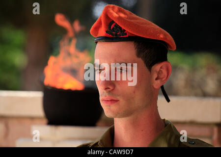 Der israelische Soldat der Kommandoeinheit der Heimatfront steht fest über dem Grab eines gefallenen Soldaten am Yom Hazikaron Memorial Day für die gefallenen Soldaten im jüdischen Begräbnisplatz Kiryat Shaul im Norden von Tel Aviv, Israel Stockfoto