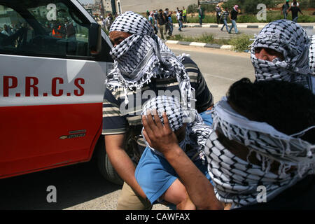 26. April 2012 - Ramallah, Westjordanland, Palästina - Palästinenser tragen einen verwundeten Demonstrator Verletzte bei Zusammenstößen mit israelischen Soldaten an der Bitwonia Kreuzung außerhalb des israelischen militärischen Gefängnisses von Ofer, auf 64. Unabhängigkeitstag Israels, 26. April 2012. Palästinenser inszeniert ihre Hinweisschild Stockfoto