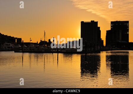 Ein dramatischer und wunderschöner Sonnenaufgang mit Gebäuden und Booten in Silhouette, die sich in den Gewässern von Baltimores Inner Harbor Harbour Maryland, USA, widerspiegeln. Freitag, 27. April 2012. Stockfoto