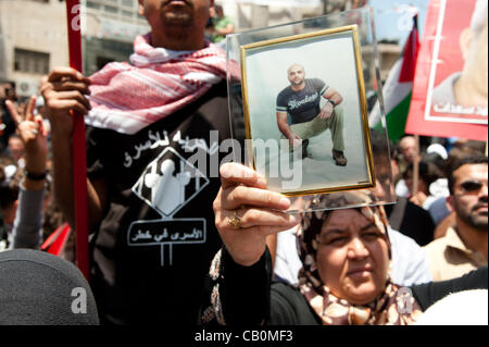 RAMALLAH, Palästinensische Autonomiegebiete - 15. Mai 2012: Eine palästinensische Frau trägt ein Porträt des Sohnes neben einem Mann trägt eine T-shirt mit dem Ausdruck ihrer Unterstützung für palästinensischen Gefangenen in israelischen Gefängnissen inhaftiert. Stockfoto