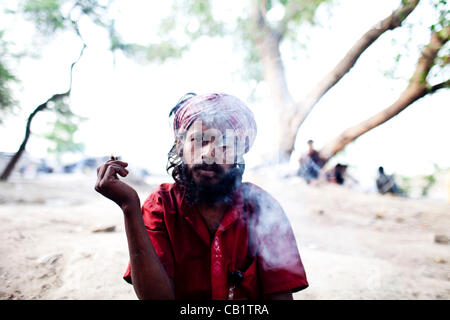 18. Mai 2012 - Neu-Delhi, Indien - ein Medikament Benutzer nimmt der erste Zug seiner Bidi-Zigarette, sitzen im Schatten eines Baumes, die Wärme von einem Delhi Sommertag zu vermeiden. Ca. 1.200 Drogenabhängige Leben auf den Straßen in den Basar, ein Gebiet, das etwa zwei Kilometer von zwei Kilometer. (Cr Stockfoto