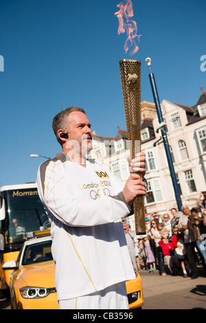 Am 10. Tag des Olympischen Fackellaufs durch das Vereinigte Königreich trägt Radio 1 DJ CHRIS MOYLES die ikonische Fackel aus Aberystwyth wie es auf seinem Weg nach Bangor in North Wales Aberystwyth Wales UK, 28. Mai 2012 weiter Stockfoto