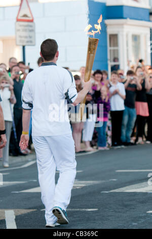 Der 10. Tag des Olympischen Fackellaufs durch das Vereinigte Königreich, trägt ein lokales Mitglied der Stadt die ikonische Fackel entlang der Promenade in Aberystwyth Wales bevor die Fackel in Nord-Wales Bangor, 28. Mai 2012 Reisen wird Stockfoto