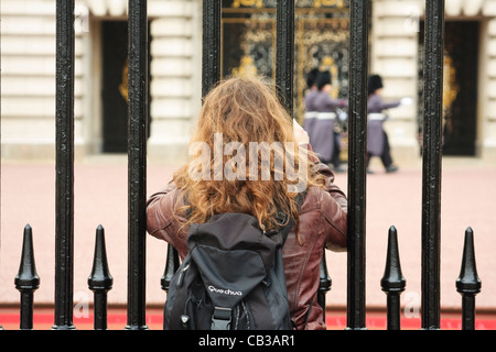 Ein Tourist nimmt ein Bild der Königinnenwache, als es vorbei auf Patrouille am Buckingham Palace, Westminster, London geht Stockfoto