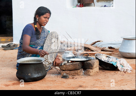 Junge indische Frau in einem ländlichen Dorf Chapati am offenen Feuer vor ihrem Haus machen. Andhra Pradesh, Indien Stockfoto