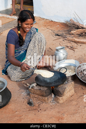 Junge indische Frau in einem ländlichen Dorf Chapati am offenen Feuer vor ihrem Haus machen. Andhra Pradesh, Indien Stockfoto