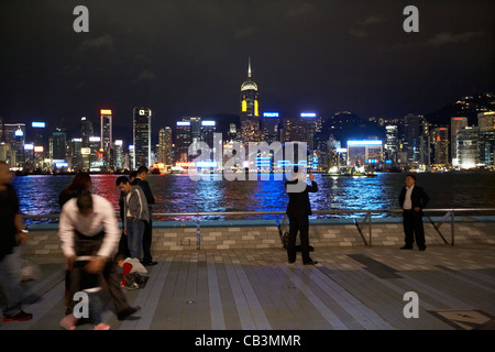 Menschen zu Fuß entlang der Avenue of Stars mit Hong Kong Island und Victoria Hafen im Hintergrund Tsim Sha Tsui Kowloon Hong ko Stockfoto