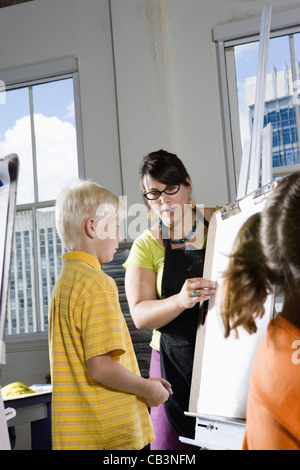 Ein Lehrer mit ihren Schülern auf Staffeleien im Kunstunterricht Stockfoto