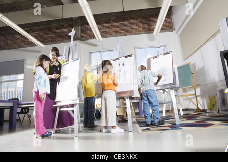 Kunstlehrer mit ihrem Schüler auf Staffeleien im Kunstunterricht Stockfoto