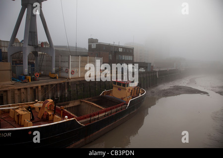 Dichter Nebel in London. Unheimliche Atmosphäre als Dichter Nebel steigt in Deptford. Eine alte industrial-Szene mit einem Lastkahn und Creek. Stockfoto