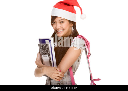 Asiatische Schulmädchen rote Weihnachtsmann Hut mit Rucksack hält Zusammensetzung Buch und notebooks Stockfoto