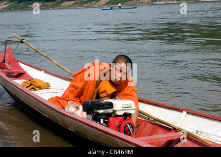 Ein junger Mönch sitzt in einem Boot auf dem Mekong in Luang Prabang Laos. Stockfoto