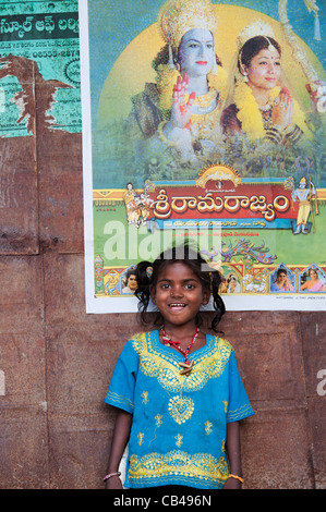 Armen indischen nomadischen Bettler Mädchen steht vor einem indischen Rama Filmplakat auf einer Hütte. Andhra Pradesh, Indien Stockfoto