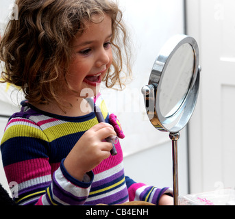 Junge Mädchen spielen aufstellen machen auf vor Spiegel England Stockfoto