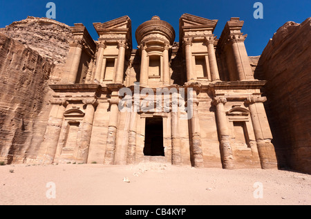 Das imposante Deir (Kloster) Gebäude erhebt sich über dem Wüstensand mit tiefblauen Himmel im Hintergrund bei den Ruinen von Petra, Jordanien Stockfoto
