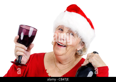 Oma oder Frau Claus hat eine tolle Zeit bei der Weihnachtsfeier hat sie trinkt und lacht während des Tragens des Weihnachtsmannes Mütze Stockfoto