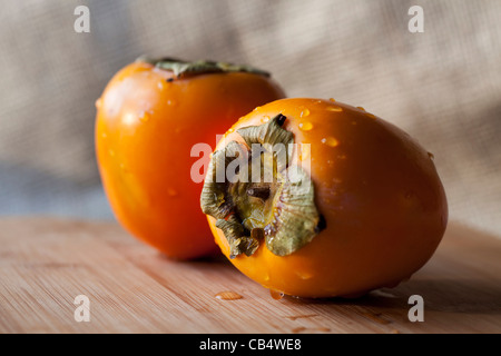 Zwei frische Kaki auf Schneidebrett. Stockfoto