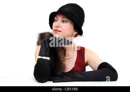 Junge schöne Dame in schwarz retro Hut und Handschuhe, tragen Perlenkette und Armband, sitzen und auf der Suche zur Seite. Stockfoto