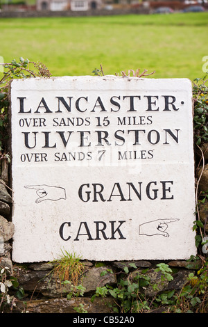 Eine alte Straßenschild Entfernungen von Cark in Cartmell, über den Sand der Morecambe Bay, Cumbria, UK zu geben. Stockfoto