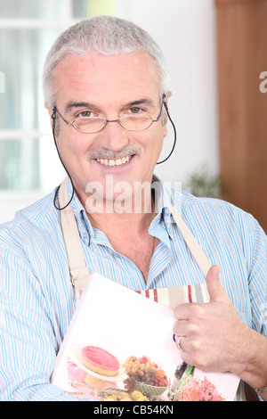 Lächelnde reifer Mann trägt Schürze Stockfoto