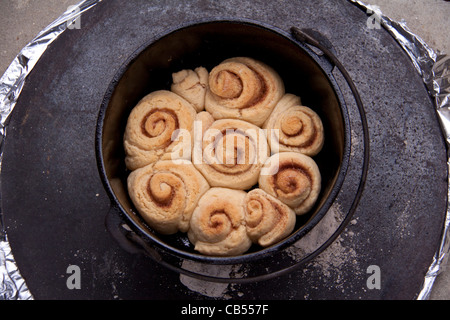 Zimtschnecken gekocht in Gusseisen "schwarzes Eisen" Dutch Oven Topf mit heißen Kohlen. Stockfoto