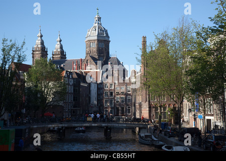 Blick auf einen Kanal mit Sint Nicolaaskerk im Hintergrund. Amsterdam, Niederlande. Stockfoto