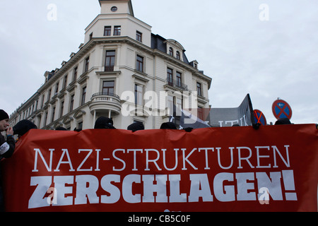 Antifaschistische Teilnehmer halten während einer Kundgebung gegen den Rechtsextremismus und das Parteizentrum der Neo-Nazi-NPD in Leipzig ein Banner in deutschen "Nazi-Strukturen" Stockfoto