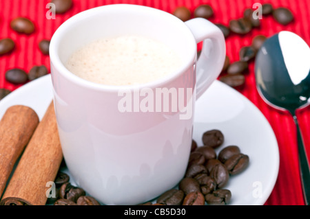 Kaffeetasse mit Zimt, Kaffeekörner und einen Löffel von der Seite. Stockfoto