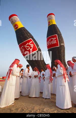 Junge saudische Männer trinken Coca-Cola vor zwei riesigen gefesselte Heißluftballons Stockfoto