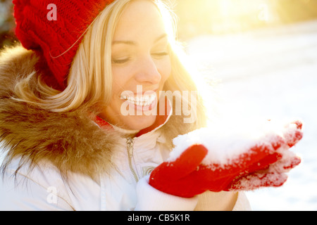 Porträt von glücklichen Mädchen hält Schnee auf Palmen mit Sonnenschein über Ihr Stockfoto