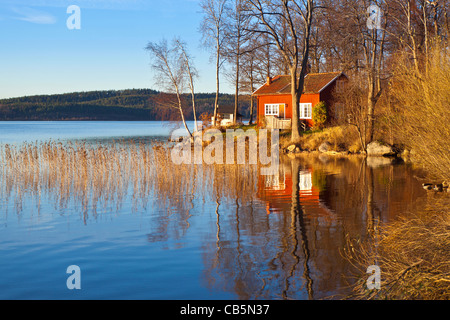 Typische schwedische oder Skandinavischen roten Holzhaus an einem See. See Sävelången, Ingared, Västra Götaland, Schweden Model Release: Nein Property Release: Nein Info: Photograph Verständnis (aber nicht garantiert) ist, dass Eigentum Freigabe ist nicht für private Eigenschaften für die gewerbliche Nutzung nach dem schwedischen Gesetz für Bilder aus öffentlichen Land-/Straße genommen. Bild von der öffentlichen Straße genommen. Stockfoto