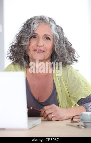 Grauhaarige Frau vor Laptop-computer Stockfoto