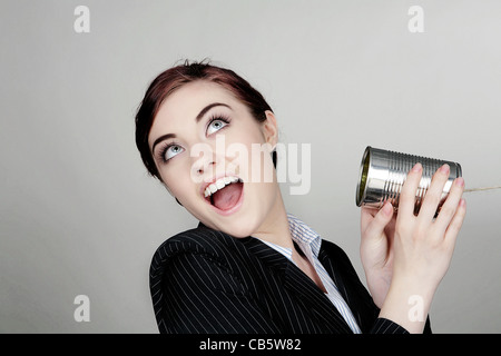 Frau in einem smart Businsess-Anzug in der Kommunikation mit einer Blechdose und string Stockfoto