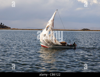 Ein Segelboot mit einem sehr alten geflickten Segel am Titicacasee, Peru Stockfoto