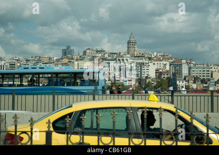 Auf der Suche von Istanbuls Eminönü Platz in Richtung der Galata-Turm vorbei ein gelbes Taxi und bus Stockfoto