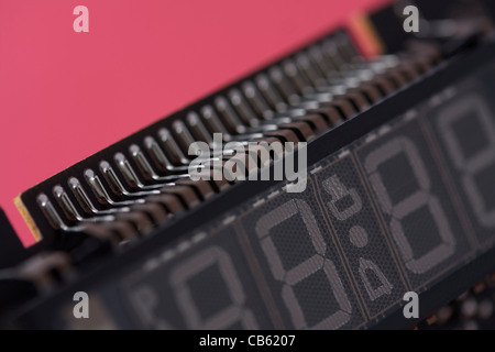 Nahaufnahme der digitalen Display und integrierten Schaltkreisen Pins vor rotem Hintergrund. Minimale Fokus auf einzelnen Pins. Stockfoto