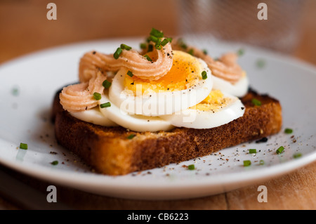 Klassische schwedische öffnen konfrontiert Sandwich aus geschnittenem gekochtem Ei garniert mit Kalles Kaviar und mit gehacktem Schnittlauch bestreut. Stockfoto