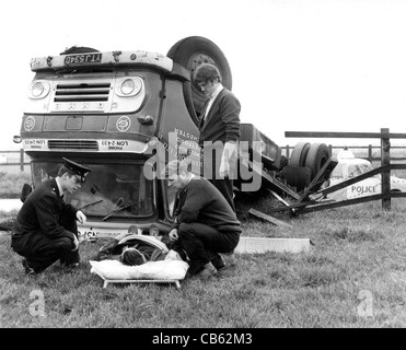 Ein Polizist und zwei Männer trösten einen verletzten Fahrer vor seinem umgekippten LKW im BILD VON DAVID BAGNALL 1967 Stockfoto