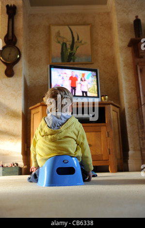 Kleinkind sitzen auf Töpfchen vor dem Fernseher Uk Stockfoto