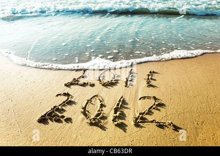 Neujahr 2012 ist kommenden Konzept - Inschrift 2011 und 2012 an einem Strand Sand, die Welle Ziffern 2011 abdeckt. Stockfoto